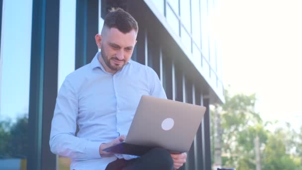 Умный Бизнесмен Использующий Ноутбук Городской Среде Сидит Перед Офисным Зданием — стоковое видео