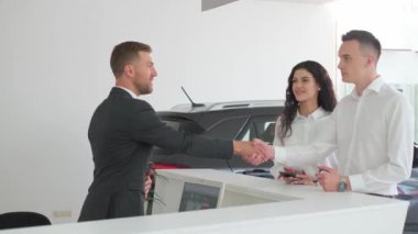 Araba galerisinde el sıkışan mutlu çift. Araba galerisi konsepti, araba satışı..
