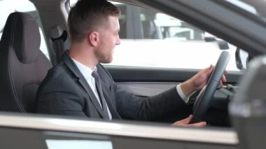 Bir işadamı yeni bir araba alır ve onu kuaförde inceler. Bir adam yeni bir arabaya bakar. Bir araba galerisinde tüketici. Araba galerisi.