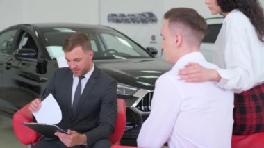 Otomobil işi, yeni araba satışı. Mutlu bir çift araba galerisindeki bir arabadan bahseden bir torbacıyla konuşur. Yeni bir araba alıyorum..