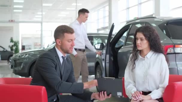 Hombre Joven Una Mujer Están Consultando Con Gerente Concesionario Automóviles — Vídeo de stock