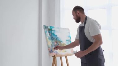 Sanatçı modern bir tablo yaratmak için bir fırça kullanır. Soyut resim.