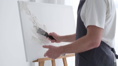 Bir sanatçı tuvale yağlı boya boyayla resim çizer. Bir sanatçı atölyedeki soyut bir yağlı boya resim üzerinde yaratıcı bir şekilde çalışır. Hobi konsepti.