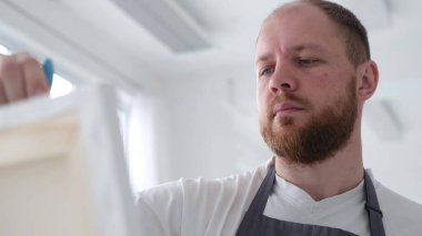 Bir sanatçı tuvale yağlı boya boyayla resim çizer. Bir sanatçı atölyedeki soyut bir yağlı boya resim üzerinde yaratıcı bir şekilde çalışır. Hobi konsepti.