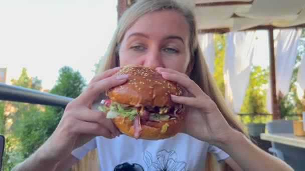 飢えた女性が大きなハンバーガーを食べる ストリートフード ジャンクフード ホットドッグ ハンバーガー ハンバーガー — ストック動画
