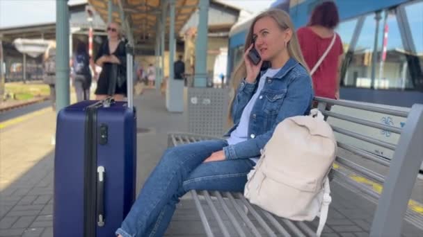 一个提着手提箱的女人正坐在长椅上 她正在欧洲的一个车站等火车 旅行概念 — 图库视频影像