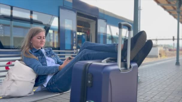 一个女人在火车站等火车的时候 一个带着手提箱的游客在等着运输 — 图库视频影像