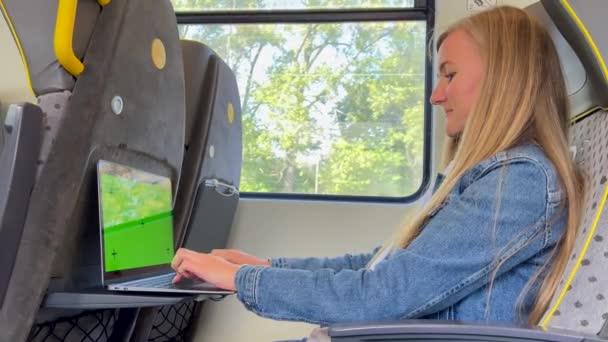 電車のラップトップで休暇中に働く若い女性 緑色のクロマ キーのラップトップ モニター — ストック動画