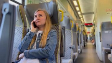 Halka açık bir metroda cep telefonuyla konuşan bir kadının portresi, koltukta oturan ve yolculuğun tadını çıkaran bir yolcu..