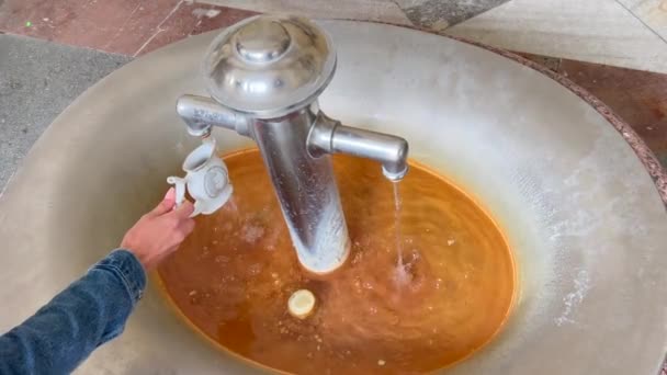 这个女孩在卡洛维谷收集治愈水 捷克共和国卡洛维瓦里市的一个天然温泉里 人们正在用手斟满一杯治愈的矿泉水 — 图库视频影像