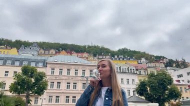 Çek Cumhuriyeti 'nin Karlovy Vary kentindeki tıbbi bir termal kaynaktan su içen bir turist kadın. Tedavi ve iyileşme veya rehabilitasyon kavramı. 