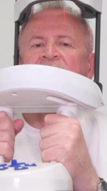 Sefalometrik soketli diş röntgeni makinesi. Yaşlı bir adam yüzünün fotoğrafını çekiyor. Yüzün görüntüsü. Dikey video.