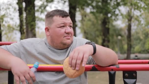 Избыточный Вес Человек Ест Бургер Время Утренних Упражнений Парке Проблема — стоковое видео