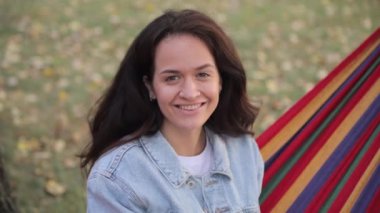 Parkta dinlenen ve hamakta oturan güzel esmer bir kadının portresi..