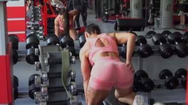 Güzel vücutlu kaslı genç bir kadın halterle egzersiz yapıyor. Sportif kız spor salonunda ağırlık kaldırıyor..