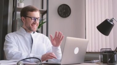 Mutlu erkek doktor internetten hastaya danışmanlık yapıyor. Bilgisayardaki webcam görüntülü arama sayesinde. Uzaktan sağlık hizmeti teletıp kavramı.