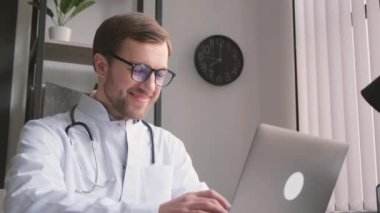 Tıp üniformalı bir adam bilgisayar klavyesinde daktilo kullanıyor. Doktor kavramı modern teknolojilerle çalışır..