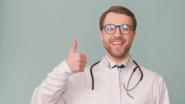 Ein Gutaussehender Arzt Weißer Arztuniform Vor Grauem Hintergrund Studio Zeigt — Stockvideo