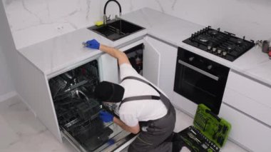 Bir adam mutfak odasına yeni bir bulaşık makinesi yerleştiriyor..