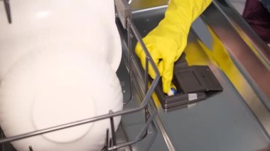 Bir kadın bulaşıkları yıkamadan önce bulaşık makinesine bir kapsül koyar. Bulaşık makinesini açıyorum..