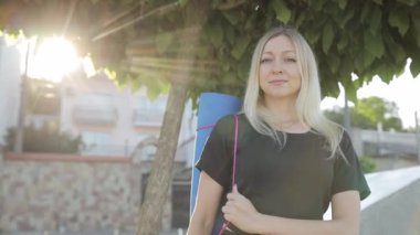 Güneş ışığında güzel bir sarışın kız kameraya bakar ve gülümser..