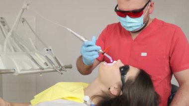 Diş hekimi ve diş hekimi ağız boşluğunda manipülasyon sağlıyor. Erkek dişçi, dişçi, dişçi stüdyosunda dişçiden kadın hastaya diş çıkarıyor.