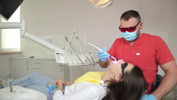 歯科医は歯科医院で患者を治療する 医者は歯科医の椅子で女性の歯を扱う — ストック動画