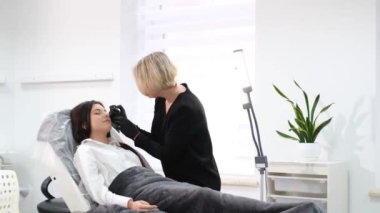 Güzellik salonundaki kirpik okçu kadına kalıcı makyaj dövmesi uygulanıyor. Güzellik salonundaki genç bir kadın, bir güzellik uzmanının göz kalemi ve kalıcı makyaj yapmasını sever.. 