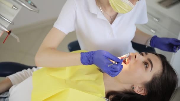 医師は 現代的な機器の助けを借りて患者の口腔を検査する 歯医者の予約で美しい女性 — ストック動画