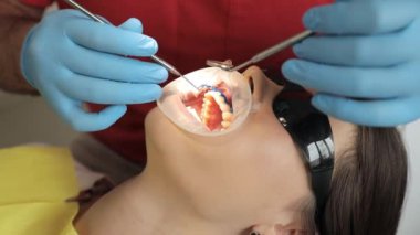 Tıbbi ekipman kullanan bir dişçinin yakın çekimi bir hastayla dişçi muayenehanesinde çalışır..