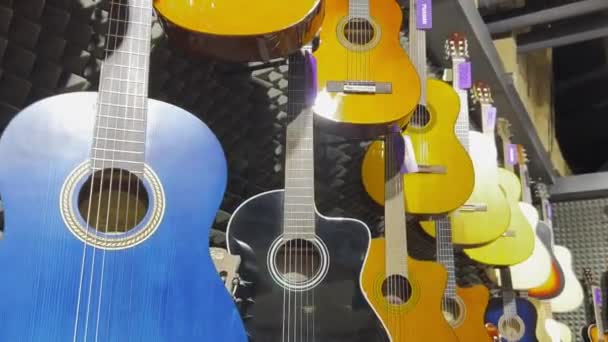 多くのカラフルなクラシックギターが店の壁に掛かります — ストック動画