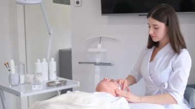 Bir güzellik uzmanı bir kadının yüzüne gençleştirici iğneler yapar..