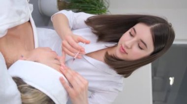 Dikey video, bir güzellik uzmanı bir kadının yüzüne gençleştirici iğneler yapar..