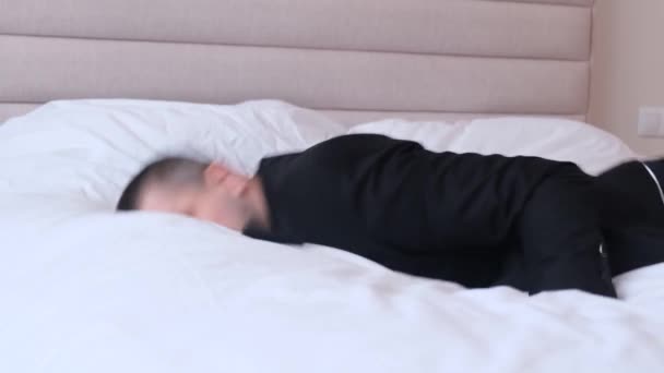 一个穿西装的年轻人倒在床上 精疲力竭的商人在长途飞行 时区后躺在床上休息 业务概念 — 图库视频影像
