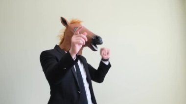 At maskesi takmış dans eden genç bir adam, ritmik olarak ellerini stüdyonun arka planında yukarı kaldırıyor..