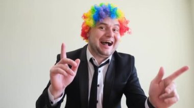 Renkli peruklu dans eden genç bir adam ellerini stüdyo arka planında ritmik bir şekilde hareket ettiriyor..
