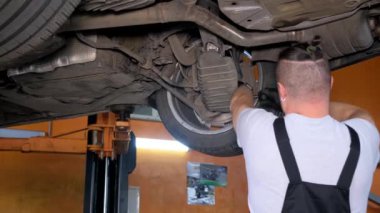 Hippi tamirci araba servisinde aracın altında çalışıyor. Araba servisinde çalışan uzman bir tamirci..