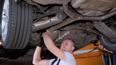 Yetişkin erkek binicilik uzmanları oto tamirhanesinde çalışıyor. Otomobil tamircisi garajdaki arabanın durumuna baksın..