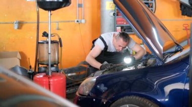 Arabanın yağını değiştiriyorum. Araba servisinde çalışırken oto tamircisi.