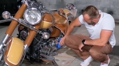Yakışıklı bir adam retro motorsikletini siliyor. Araba ve motosiklet koleksiyoncusu..