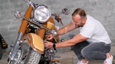 Atölyede motosiklet tamir eden kendine güvenen genç bir adam. Bir araba tamircisi atölyede bir motosikleti tamir eder.. 
