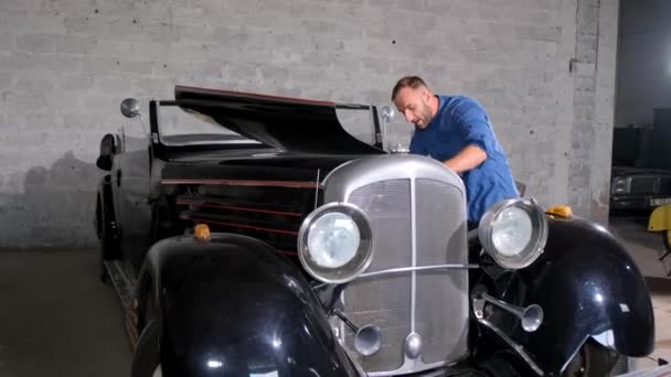 Ένας Αρσενικός Μηχανικός Επισκευάζει Ένα Ρετρό Αυτοκίνητο Ένα Γκαράζ — Αρχείο Βίντεο