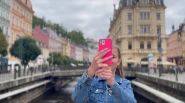 Bir kadın turist akıllı telefonuyla güzel bir Avrupa şehrinin fotoğraflarını çekiyor..