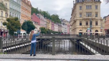 Güzel bir kız eski bir Avrupa şehrinin fotoğrafını çekmek için akıllı telefon kullanır. Seyahat kavramı.