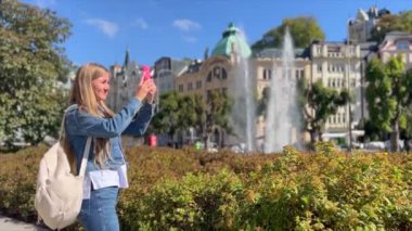 Çek Cumhuriyeti 'nin güzel turist kasabası Karlovy Vary' nin akıllı telefonuyla fotoğraf çeken bir kadın..