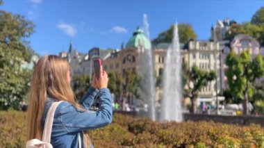Bir kadın turist, akıllı telefonuyla çekerek Avrupa şehrinin tadını çıkarıyor..