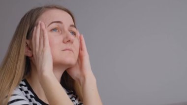 Yakından. Genç bir kadın gözlerini kapatır, kalçasına dokunur şiddetli bir baş ağrısı çeker ve kendini kötü hisseder. Hayat sıkıntıları, panik ataklar, acı verici hisler, kronik migren..