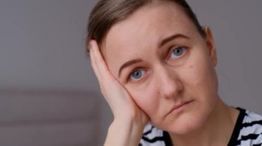 Yatakta yalnız genç bir kadın oturuyor. Evdeki depresyondaki kadın kameraya üzgün üzgün bakıyor. Kapatın. Gücenmiş kız üzgün, ilişkide sorunları var..
