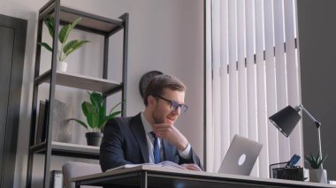 İş yerindeki genç başarılı iş adamı, iş elbisesi giymiş, laptopuyla zaferi kutluyor. Online galibiyet bildirimi alan adam, kazanan patron sevinir ve zaferi kutlar..