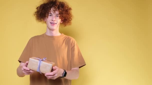 Curly Homem Com Presente Natal Suas Mãos Fundo Amarelo Estúdio — Vídeo de Stock